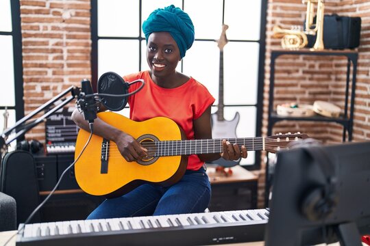 Young african american woman musician playing classical guitar at music