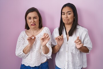 Hispanic mother and daughter together disgusted expression, displeased and fearful doing disgust...