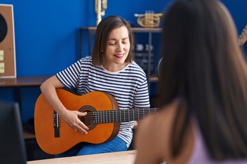 Two women musicians playing classical guitar and piano at music studio