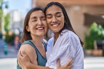 Fototapeta premium Two women mother and daughter smiling confident hugging each other at street