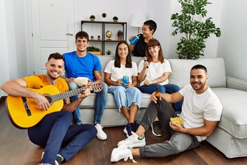 Group of young friends on party smiling happy and playing classical guitar at home.