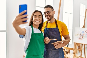 Young hispanic couple smiling happy make selfie by the smartphone at art studio.