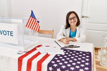 Brunette woman with down syndrome smiling writing on clipboard at election room