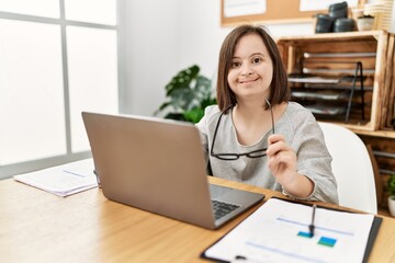 Brunette woman with down syndrome working using laptop at business office