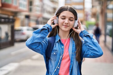 Adorable girl student listening to music at street