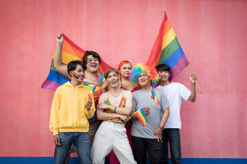 Happy Asian young friends holding rainbow flag celebrating gay pride festival - LGBTQ community concept - obrazy, fototapety, plakaty