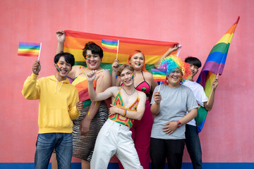 Happy Asian young friends holding rainbow flag celebrating gay pride festival - LGBTQ community...