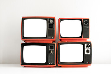Pile of red old retro television cut out blank screen on white wall background, front view