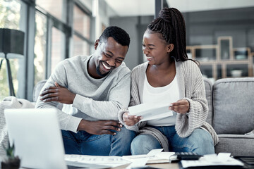 Happy black couple paying bills on a laptop at home, checking their budget and savings. Smiling...