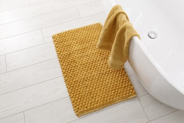 Soft orange bath mat on floor in bathroom