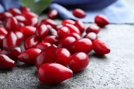 Pile of fresh ripe dogwood berries on grey table, closeup