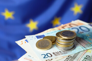 Coins and banknotes against European Union flag, closeup. Space for text - obrazy, fototapety, plakaty
