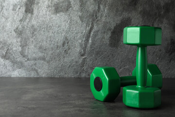 Green vinyl dumbbells on table against grey background. Space for text