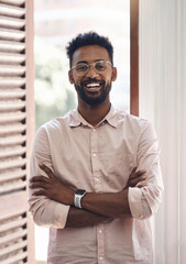 Obraz premium Happy, carefree and positive young business man standing arms crossed in his office at work. Portrait of a smiling male employee wearing glasses, looking positive and working at his job in the day