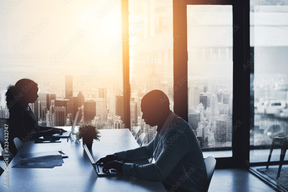 Canvas Prints Silhouette, working and sitting in the city office to focus in the morning. Business, people and typing at the boardroom table at a calm time of day. Cityscape, window and flare view of urban life.