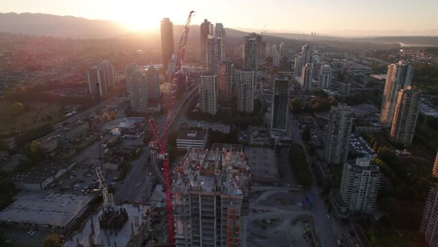 Aerial drone footage sunrise apartment buildings and crane at construction site, sunrise skyscrapers, condominiums, real estate market Vancouver, Brentwood. 4K 4096X2304 24FPS PRORES 422
