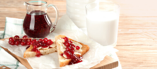 Delicious toasts with red currant jam and butter on wooden table