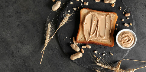 Tasty toasted bread with peanut butter on dark background with space for text