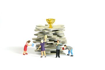 Miniature people toy figure photography. A group of student standing above puzzle jigsaw stack, with golden trophy above it, isolated on white background