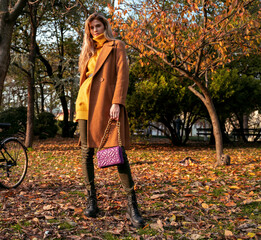 Fall fashion slim tall blonde girl in coat posing in the park in autumn 