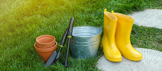 Gardening tools and gumboots on green grass outdoors