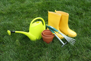 Gardening tools and gumboots on green grass outdoors