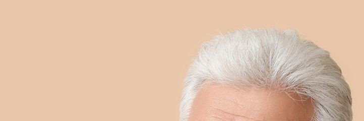 Senior man with grey hair on beige background with space for text, closeup