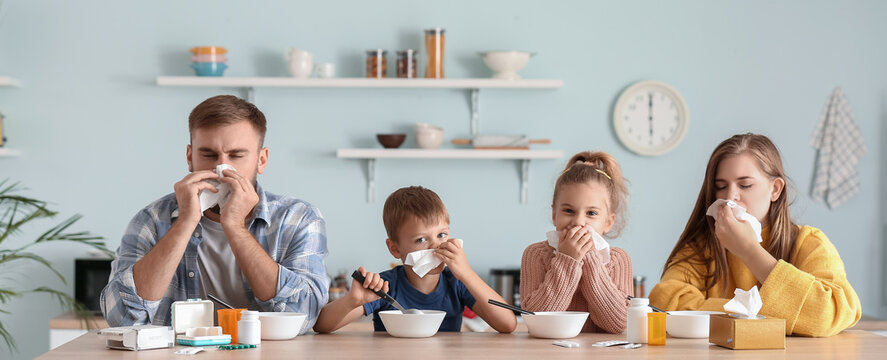 Family Ill With Flu Eating Chicken Soup In Kitchen