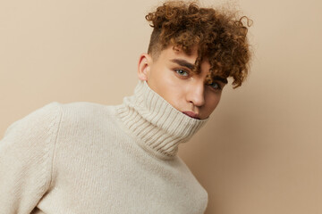 a close portrait of a handsome, attractive man with curly hair, in a light turtleneck pulled over his face