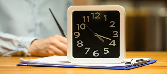 Clock with document on table in office. Time management concept