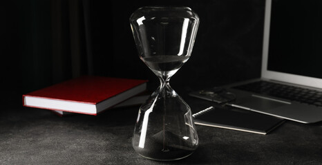 Hourglass on dark table. Time management concept - obrazy, fototapety, plakaty