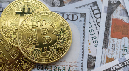 Golden Bitcoin cryptocurrency coin on banknotes of one hundred dollars.  Money exchange rate concept.