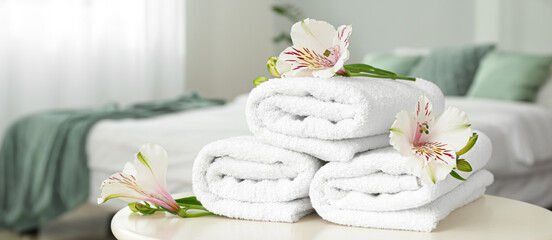 Fototapeta na wymiar Clean soft towels with flowers on table in bedroom
