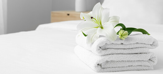 Clean soft towels and lily flowers on bed
