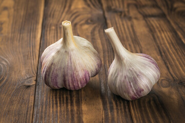 Two heads of fresh garlic on a wooden background.