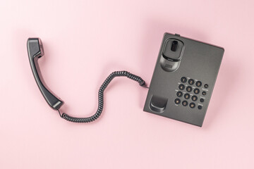Gray landline phone on a pink background. Flat lay.