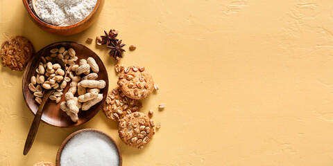 Tasty cookies with peanuts, sugar and flour on color background with space for text