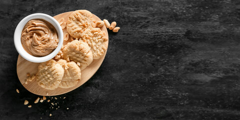 Fototapeta na wymiar Board with tasty peanut cookies and butter on black background with space for text