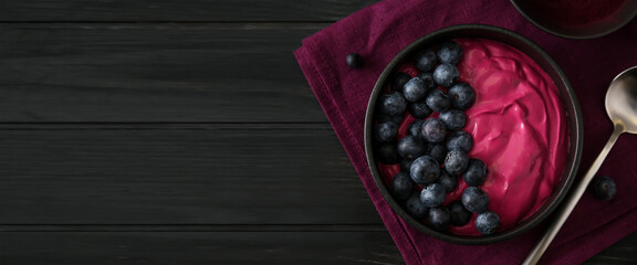 Bowl with tasty acai smoothie on dark wooden background