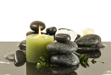 Spa stones and burning candle in water on white background
