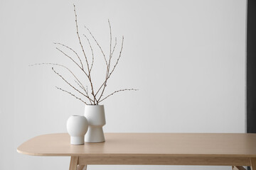 Vases with branches on table in room