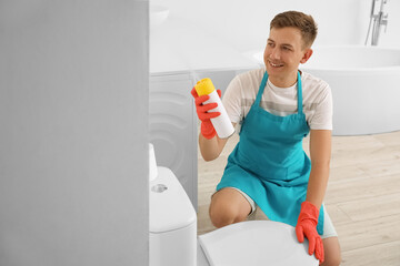 Young man with air freshener in lavatory