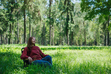 Obraz premium Portrait image of a beautiful young asian woman with closed eyes sitting on a chair in the park