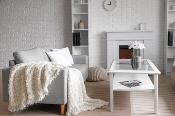 Fototapeta premium Interior of light living room with grey sofa, table and fireplace