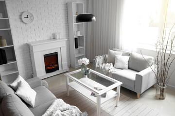 Fototapeta premium Interior of light living room with grey sofas, table and fireplace