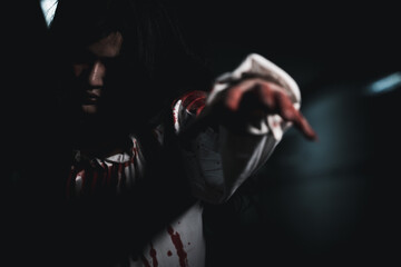 Bloody halloween makeup. Asian woman zombie with blood she death and scary at dark night in tunnel, Horror bloodthirsty ghost girl hair covering face and eye reach arm out, Happy halloween day concept