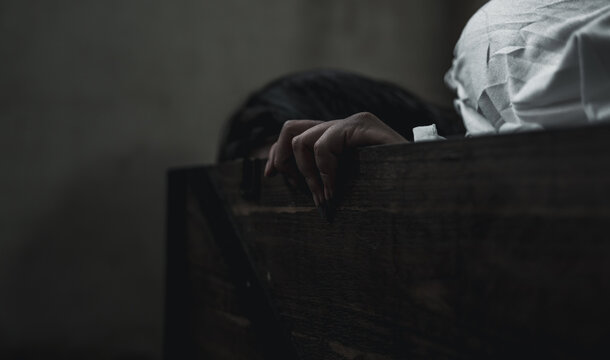Horror ghost woman. Asian ghost horror creepy scary have hair covering face and eye lying in the old treasure chest, female makeup terror zombie face, murder, Closeup hand, Happy Halloween day concept
