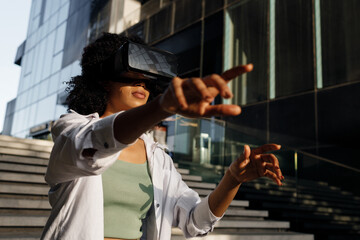 Fototapeta na wymiar Pretty young afro woman using VR glasses outdoors