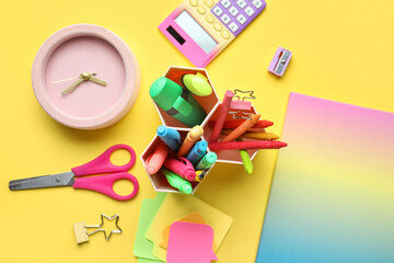 Set of different stationery with alarm clock on yellow background