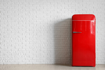Stylish retro fridge near white brick wall